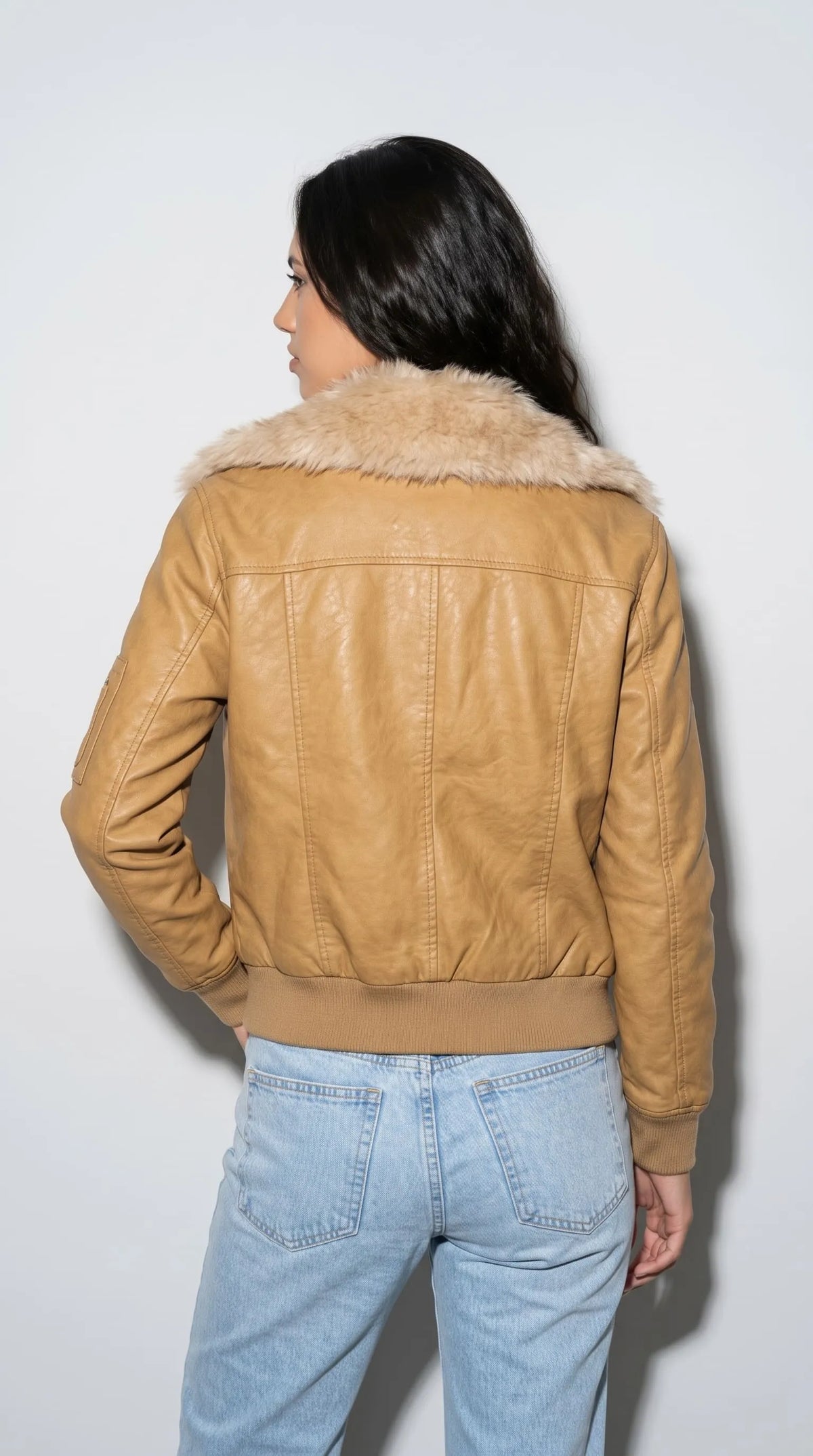 Golden ochre genuine leather flight jacket featuring a thick light-brown faux-fur collar, neatly stitched back panels and a ribbed knit hem that defines its classic cropped bomber shape. The softly creased leather surface adds character to the warm mustard shade, while the clean construction and cosy collar give this jacket a timeless aviator-inspired look for relaxed denim outfits.