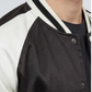 Close-up shot highlighting the seamless front snap button closure and premium fabric stitching on a classic black letterman jacket.