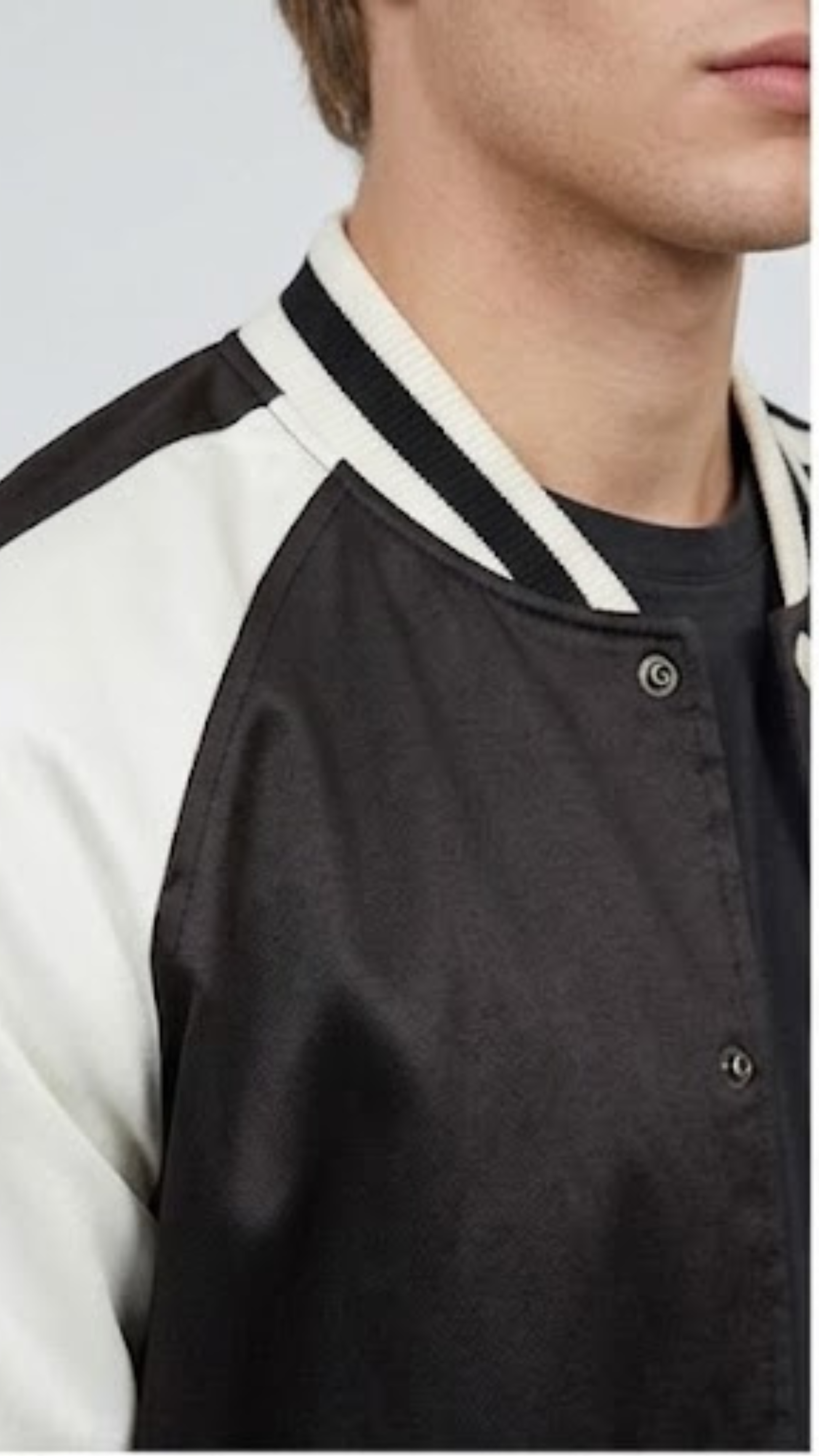 Close-up shot highlighting the seamless front snap button closure and premium fabric stitching on a classic black letterman jacket.