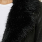 Close-up detail of premium black leather material and the soft texture of the plush black faux fur trim on a motorcycle jacket.