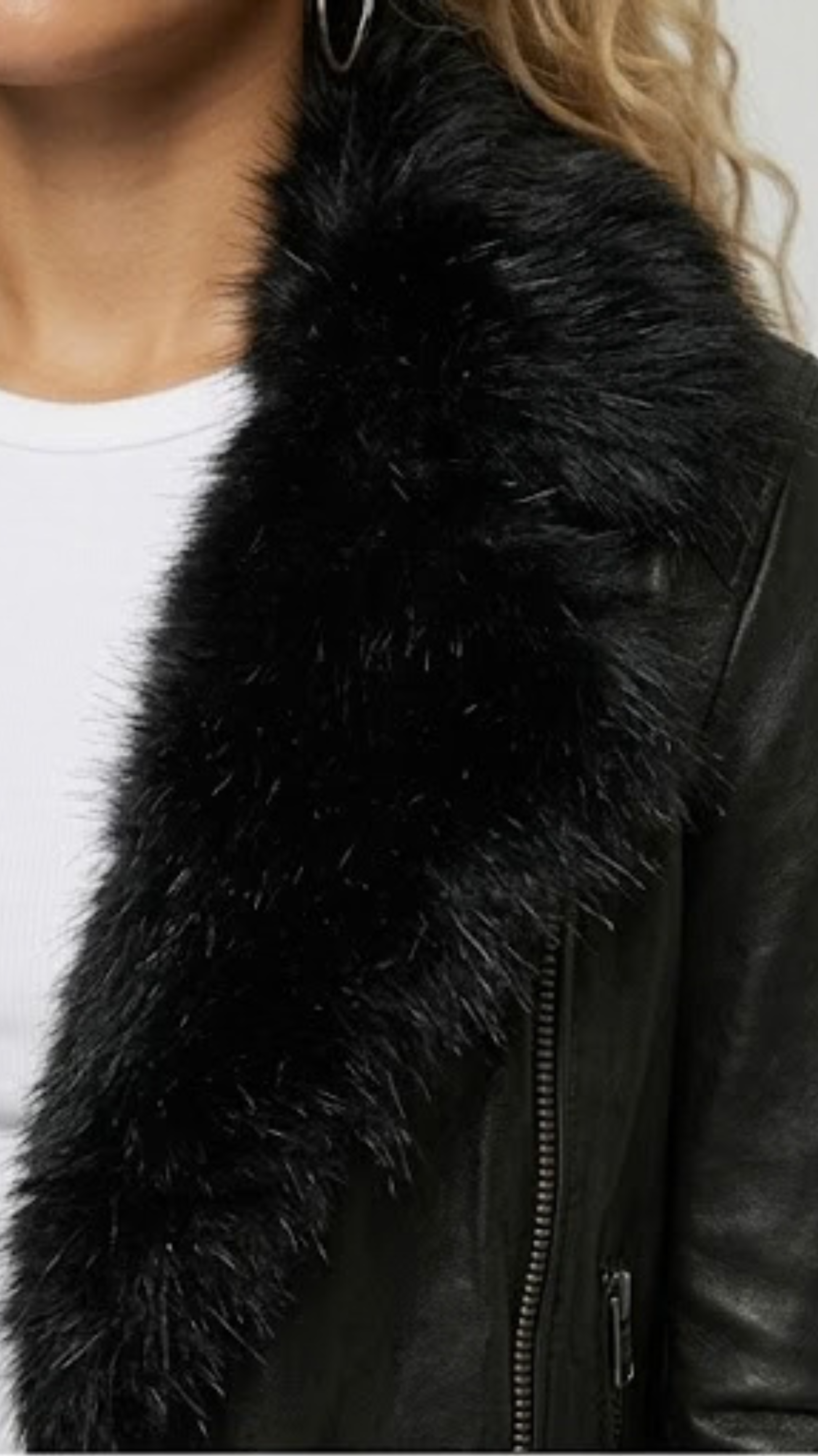 Close-up detail of premium black leather material and the soft texture of the plush black faux fur trim on a motorcycle jacket.