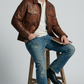 Urban lifestyle photography featuring a heritage-inspired men's winter outfit styled with a rugged dark tan distressed leather jacket.