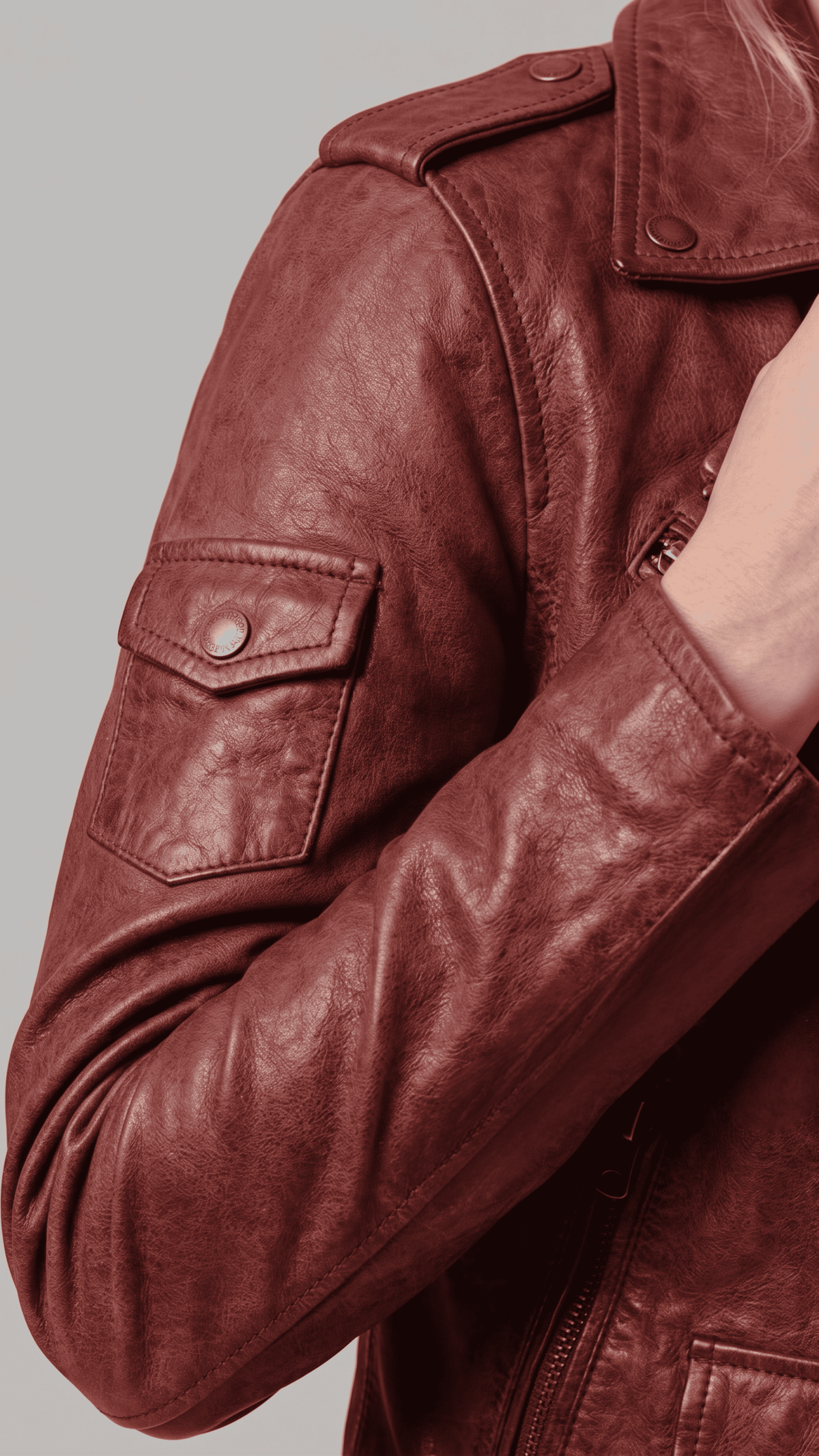 Macro view of the rich oxblood red genuine leather grain, highlighting the premium stitching quality and metallic zipper details.