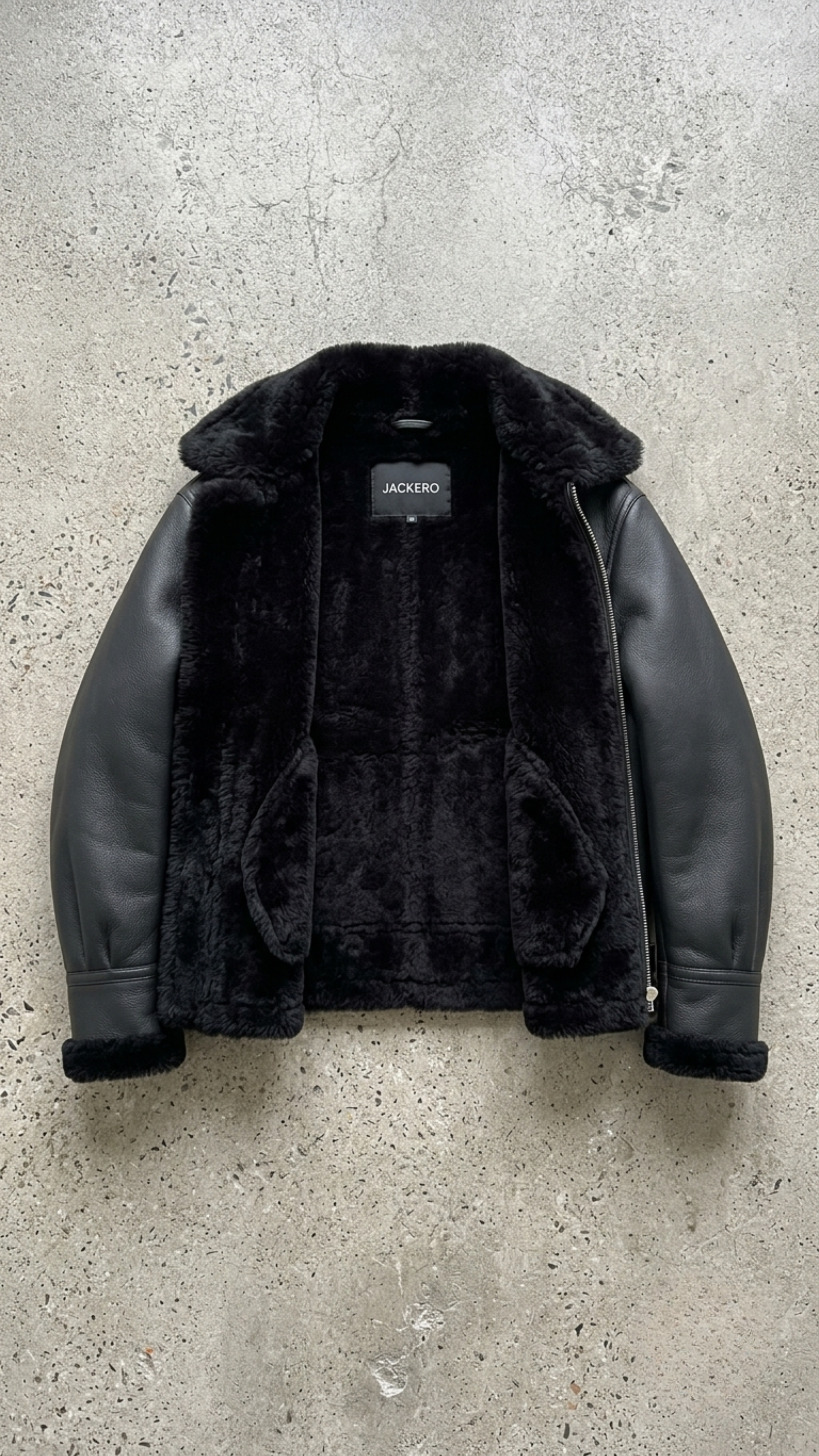 Warm black leather flight jacket with thick shearling collar on a light grey studio background.