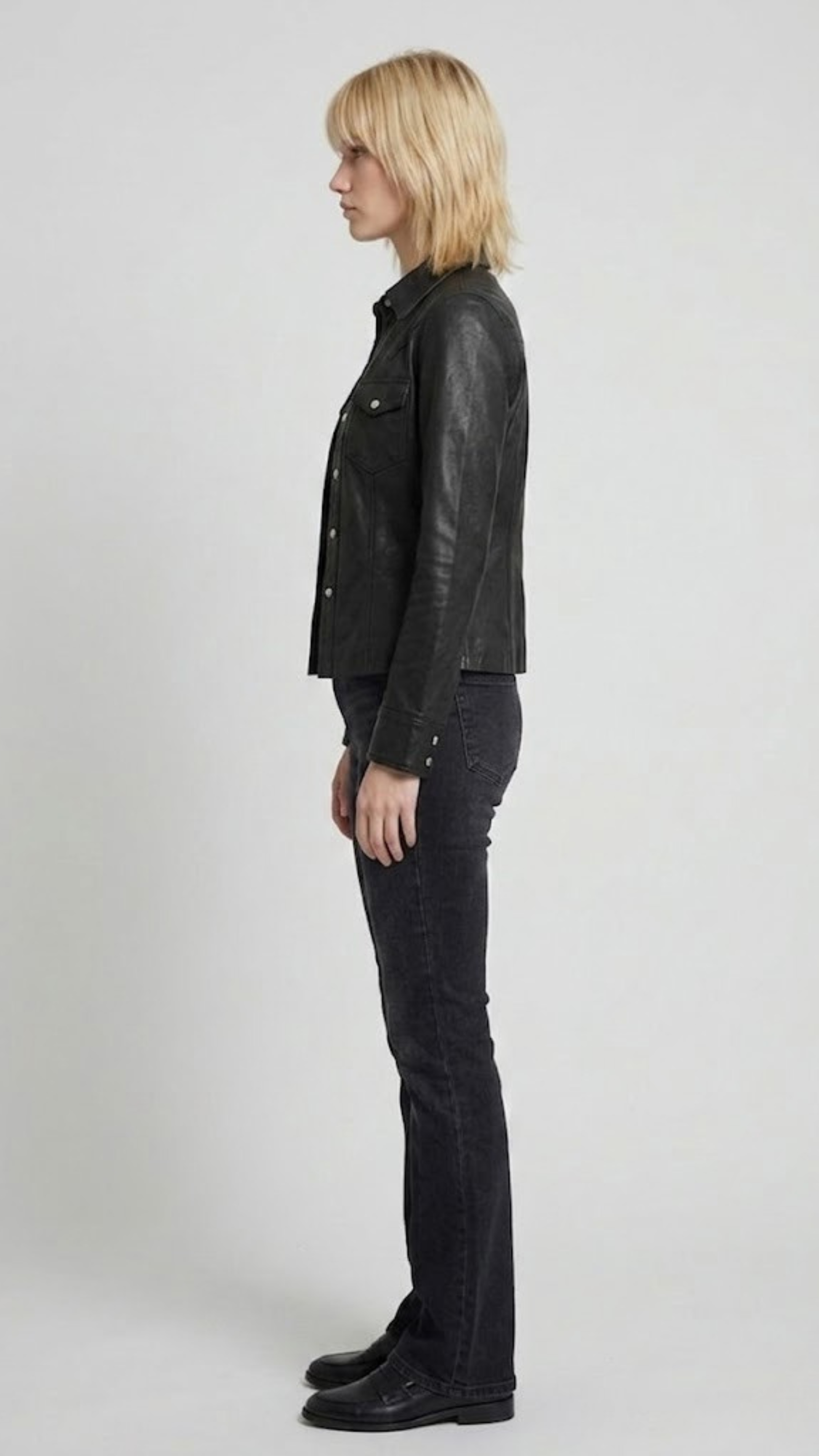 the symmetric chest flap pockets, sharp point collar, and precise stitching of a premium black leather jacket.