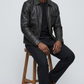 Detailed studio shot highlighting the simple band collar design, hidden zip path, and clean tailored cuffs of a premium black leather jacket.