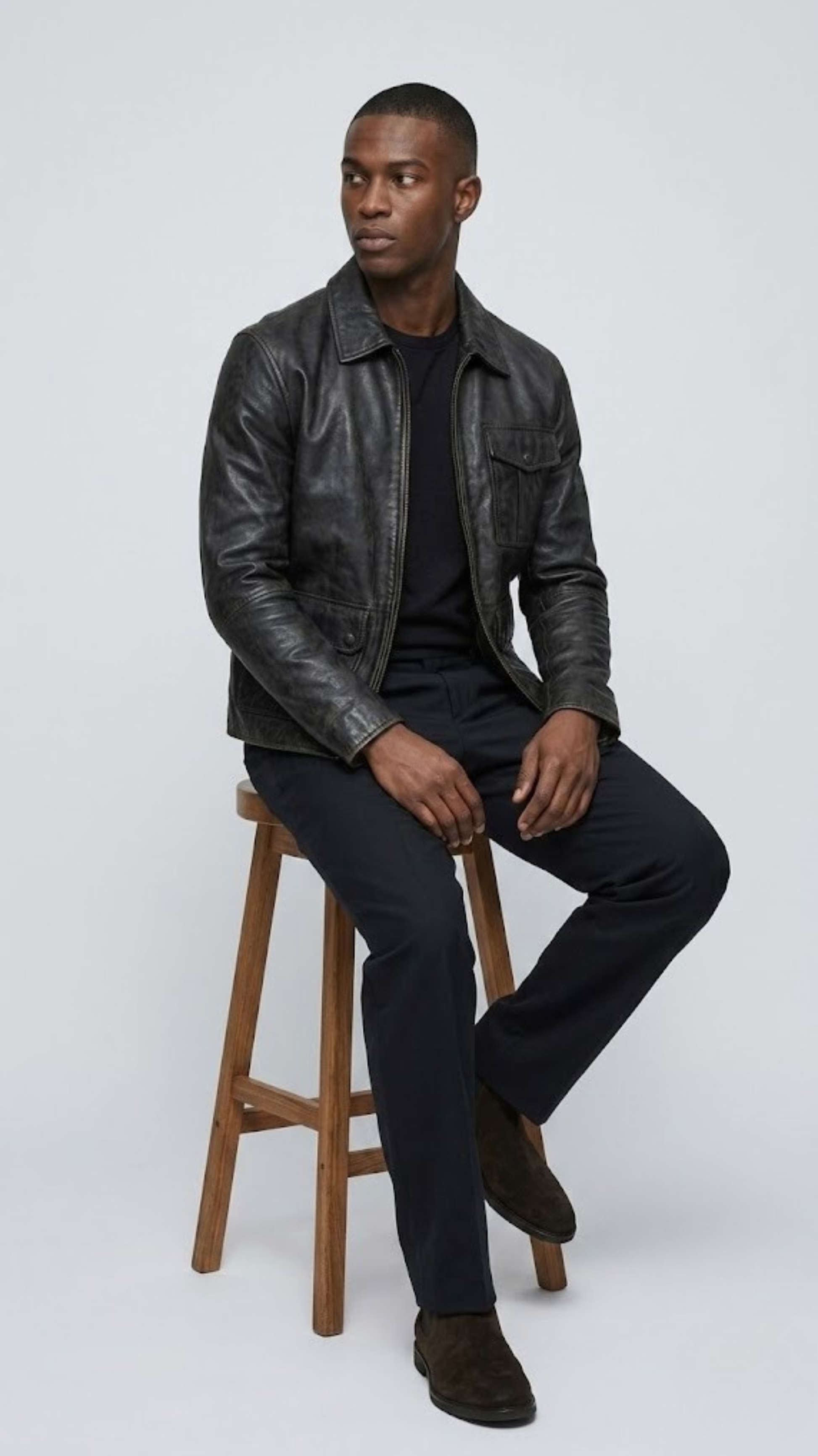 Detailed studio shot highlighting the simple band collar design, hidden zip path, and clean tailored cuffs of a premium black leather jacket.