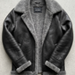 a black leather jacket highlighting the grain texture, heavy-duty zipper hardware, and thick grey shearling lining.