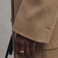 Close-up of a person wearing a beige coat with a blurred background