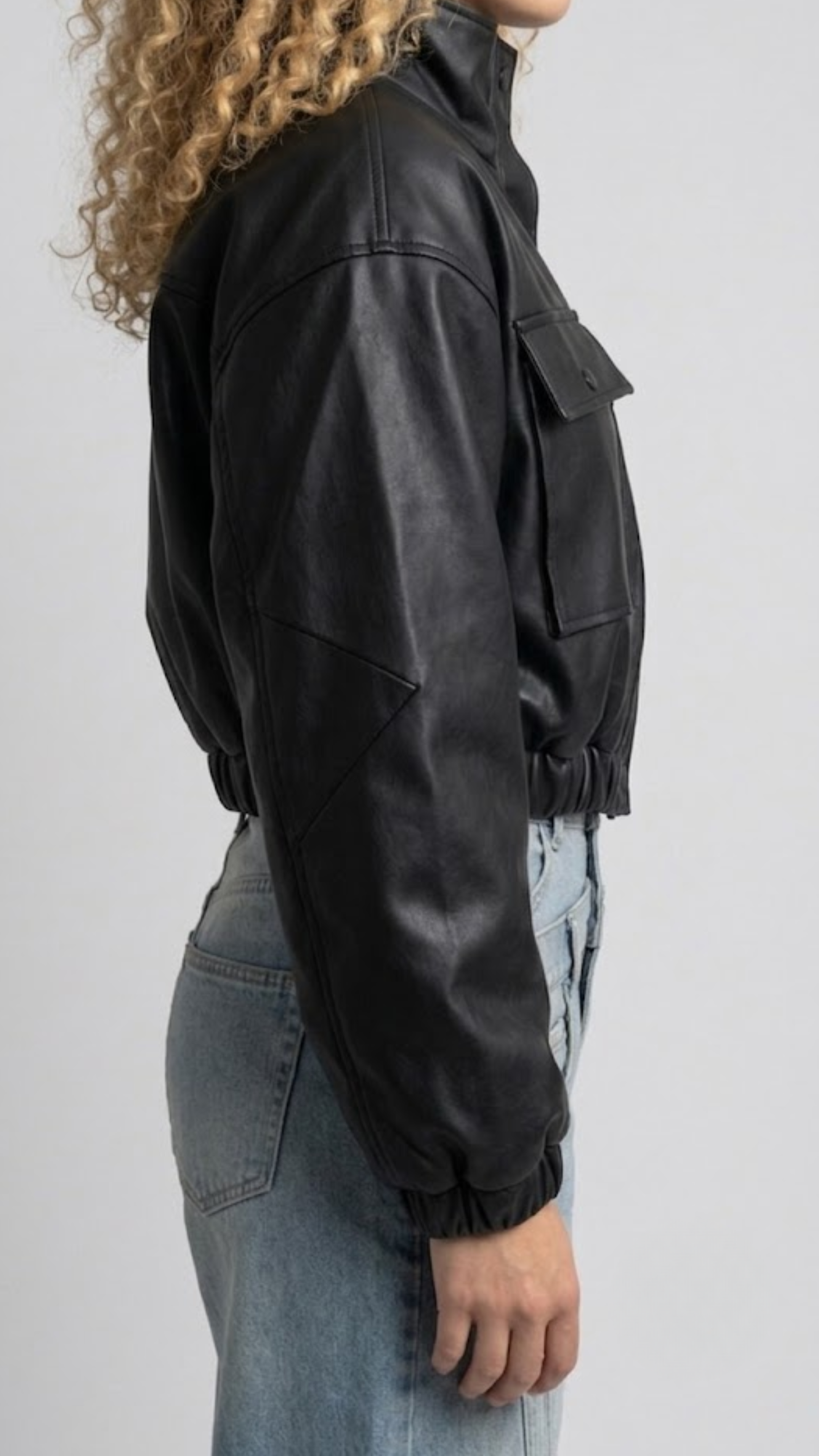 Close-up shot showing the smooth texture of high-quality black leather and precise stitching along the cropped waistband and cuffs.