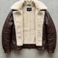 dark brown leather jacket highlighting the rich grain texture, heavy metal buckles, and soft cream shearling lining.