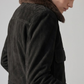 Close-up shot highlighting the velvet-soft matte finish of jet-black suede fabric contrasted with the plush dark chocolate brown faux shearling inner lining.