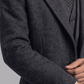 Close-up shot highlighting the rich woven texture of premium charcoal grey wool fabric and fine notch lapel stitching.