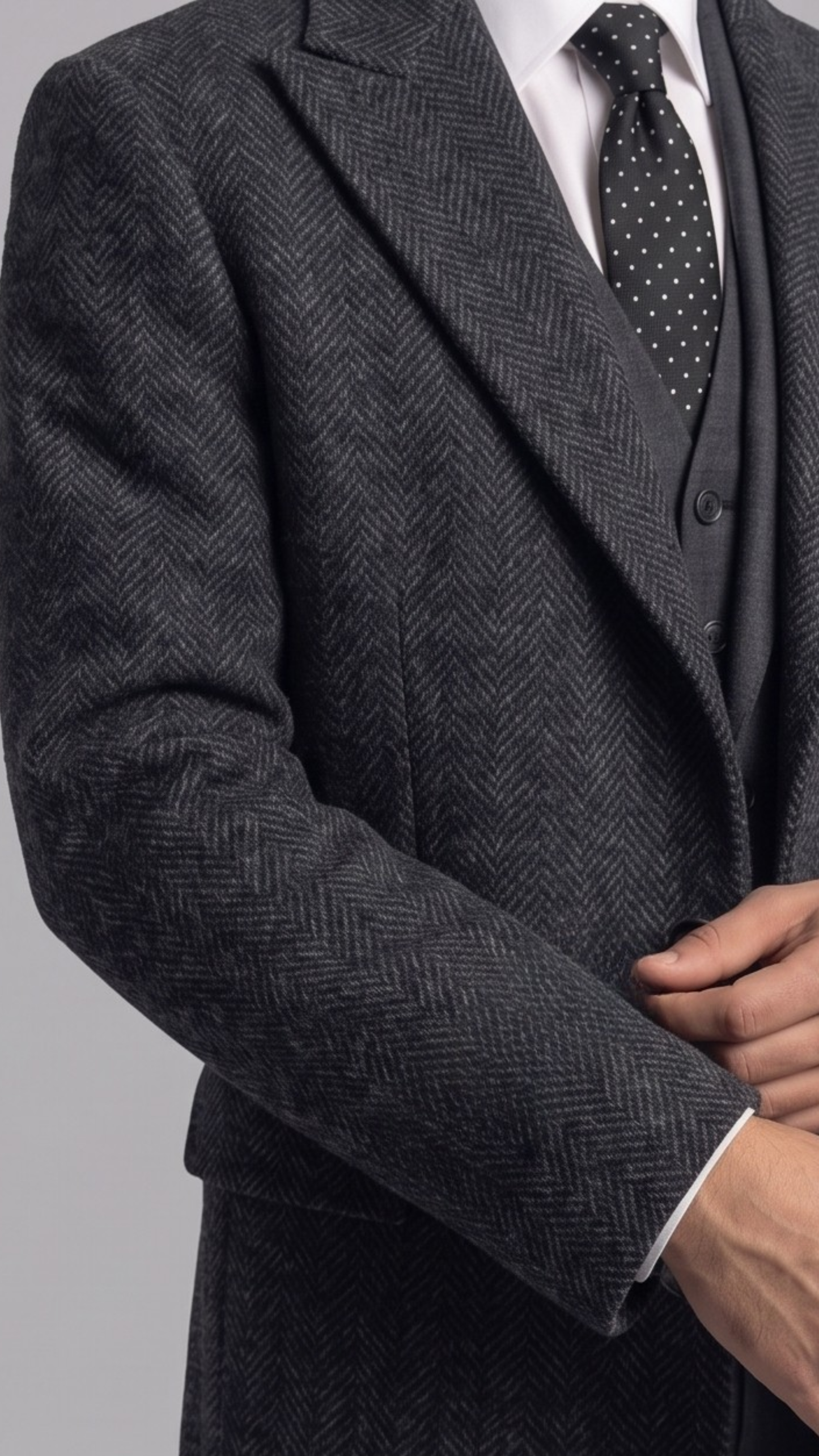 Close-up shot highlighting the rich woven texture of premium charcoal grey wool fabric and fine notch lapel stitching.