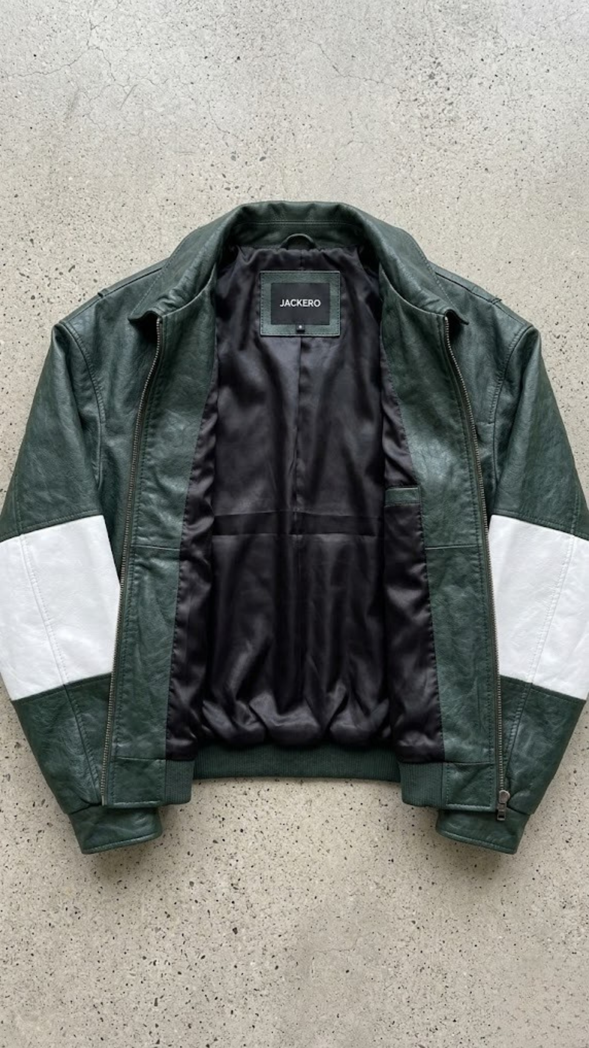 Jackero jacket flat lay photography of a premium dark green oversized leather coat with white racing stripes on a neutral grey studio background.