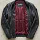 Jackero jacket flat lay photography of a high-end black leather motorcycle coat displayed symmetrically on a solid grey backdrop.