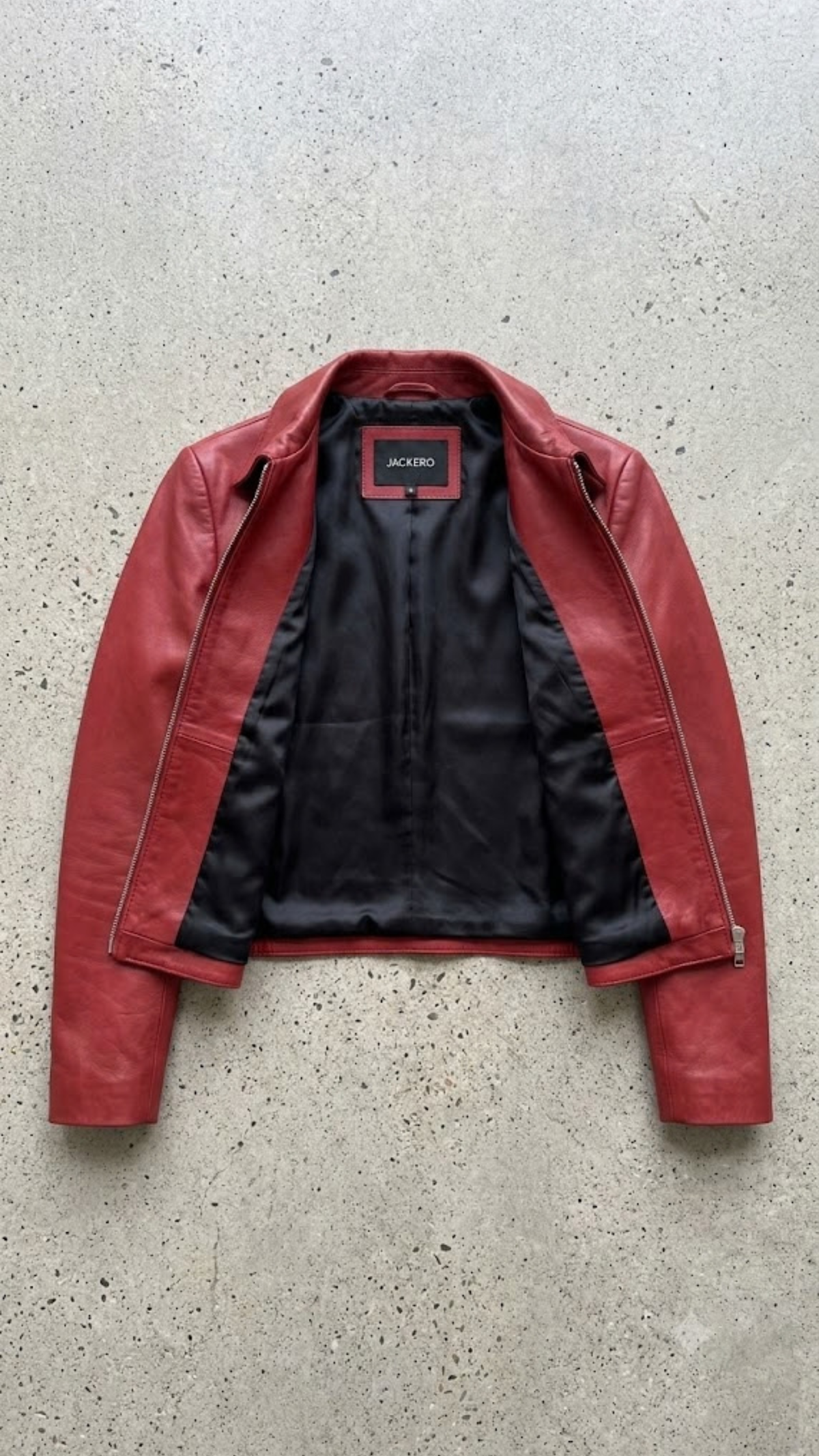 Jackero jacket flat lay photography of a high-end crimson red leather café racer coat displayed on a solid grey backdrop.
