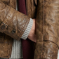 Close-up shot highlighting the unique weathered grain and distressed texture of high-quality brown leather with antique hardware details.