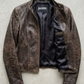 Jackero jacket flat lay photography of a high-end vintage wash dark brown leather coat displayed symmetrically on a solid neutral background.