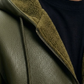 Close-up of a green leather jacket with a hood and zipper.