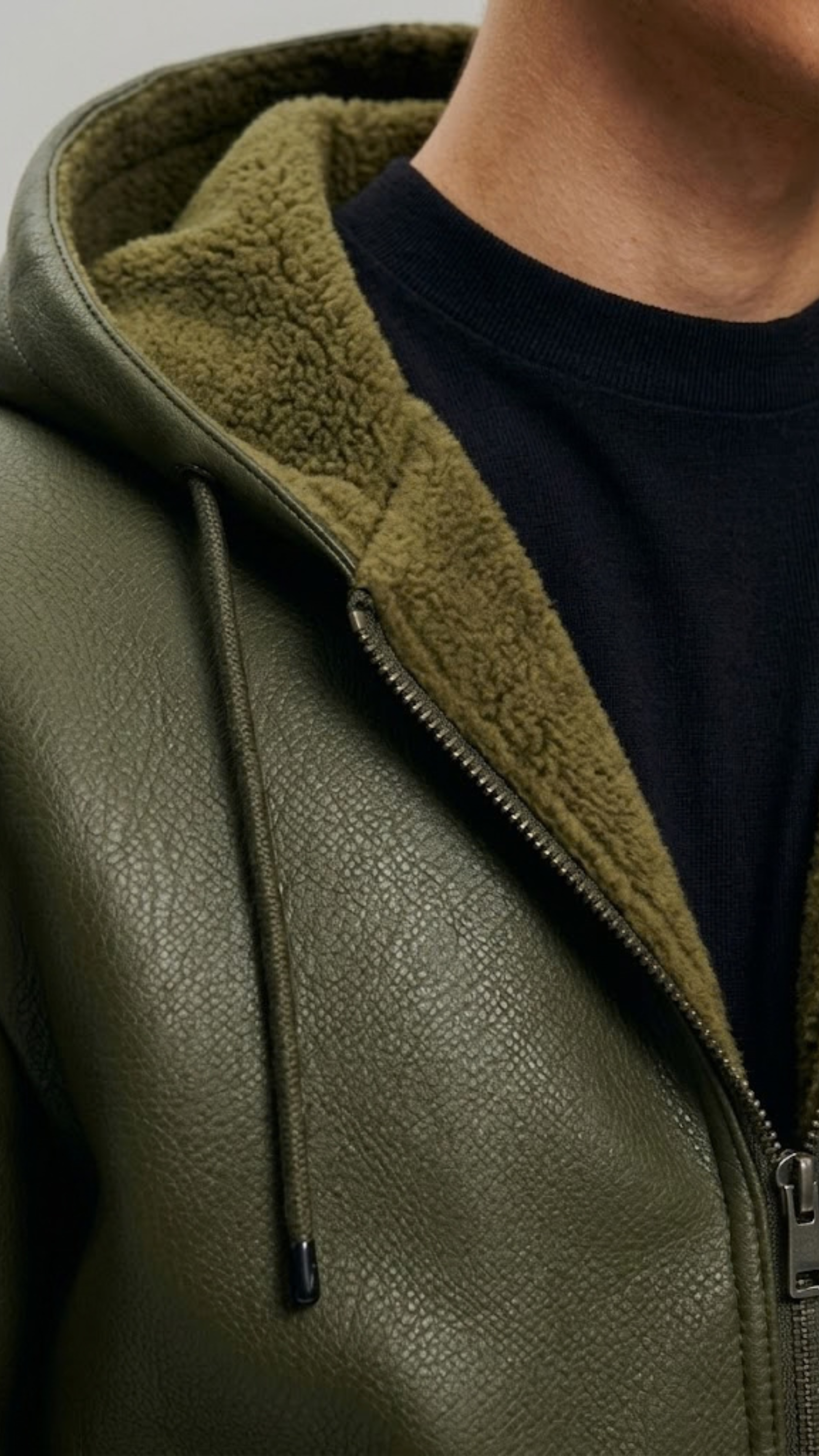 Close-up of a green leather jacket with a hood and zipper.