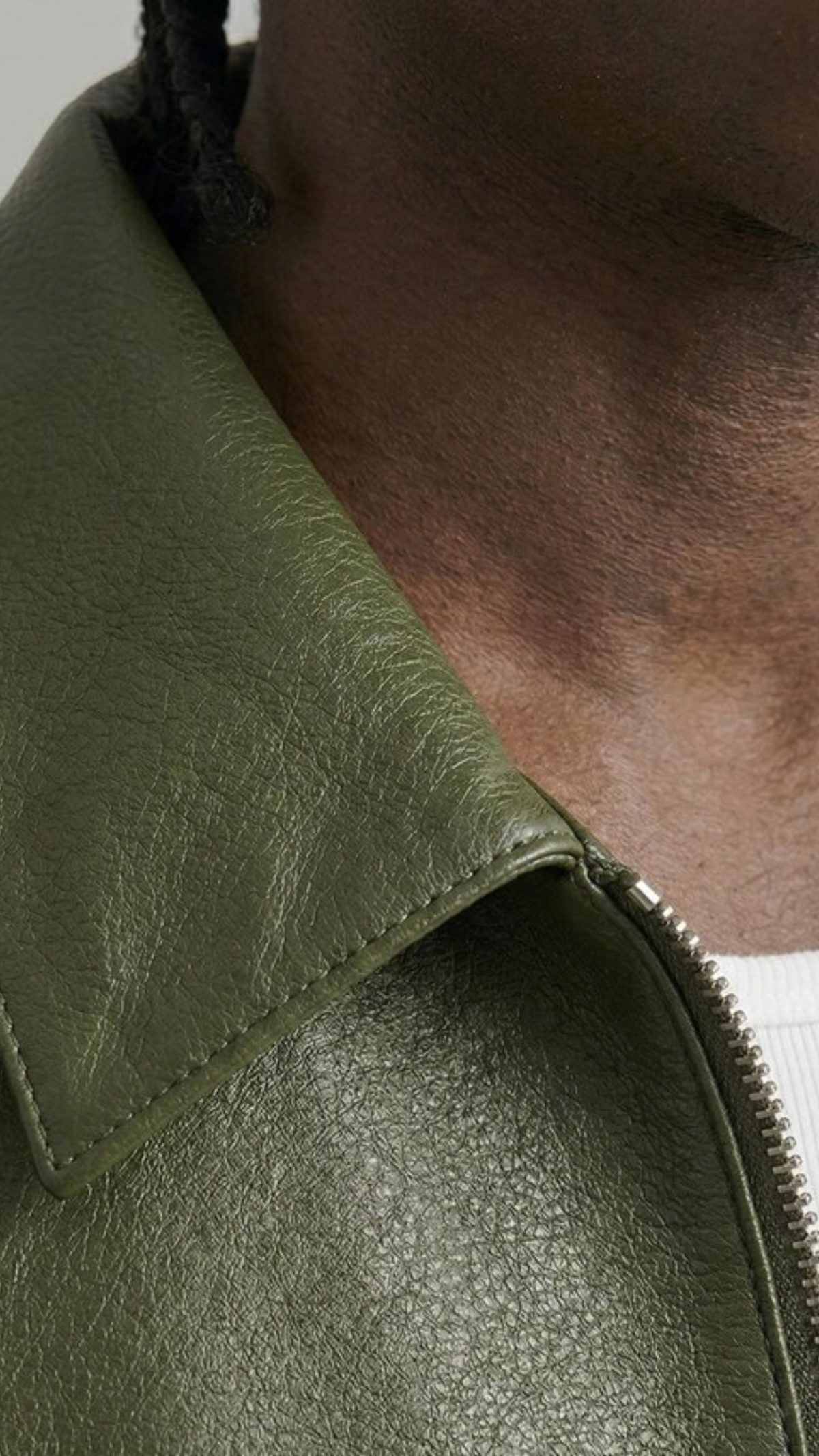 Close-up of a green leather jacket with a zipper