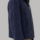 Man wearing a navy blue suede jacket on a gray background