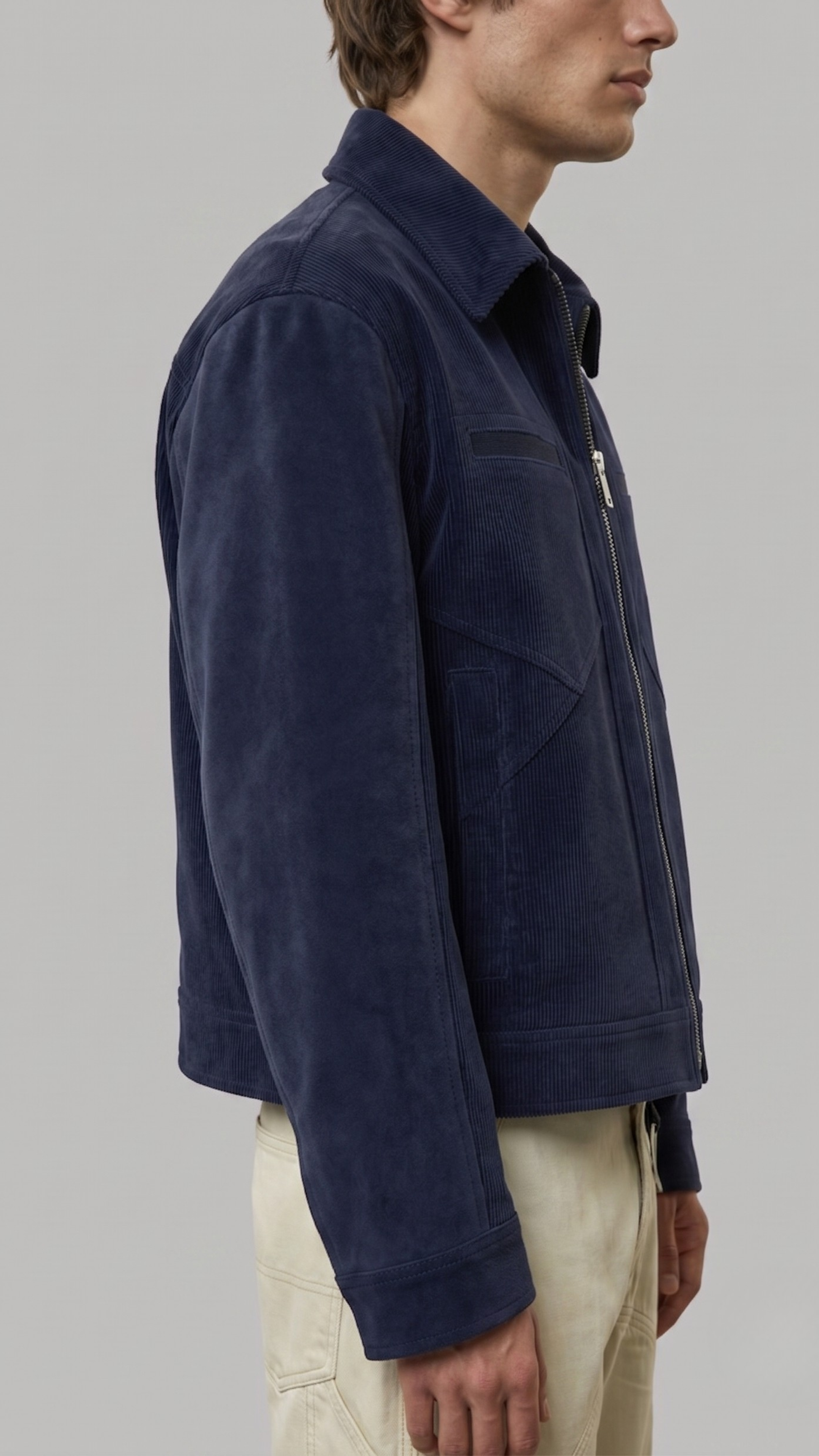 Man wearing a navy blue suede jacket on a gray background