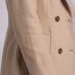 Close-up shot highlighting the soft weave texture of the beige cotton fabric and high-quality contrast button detailing.