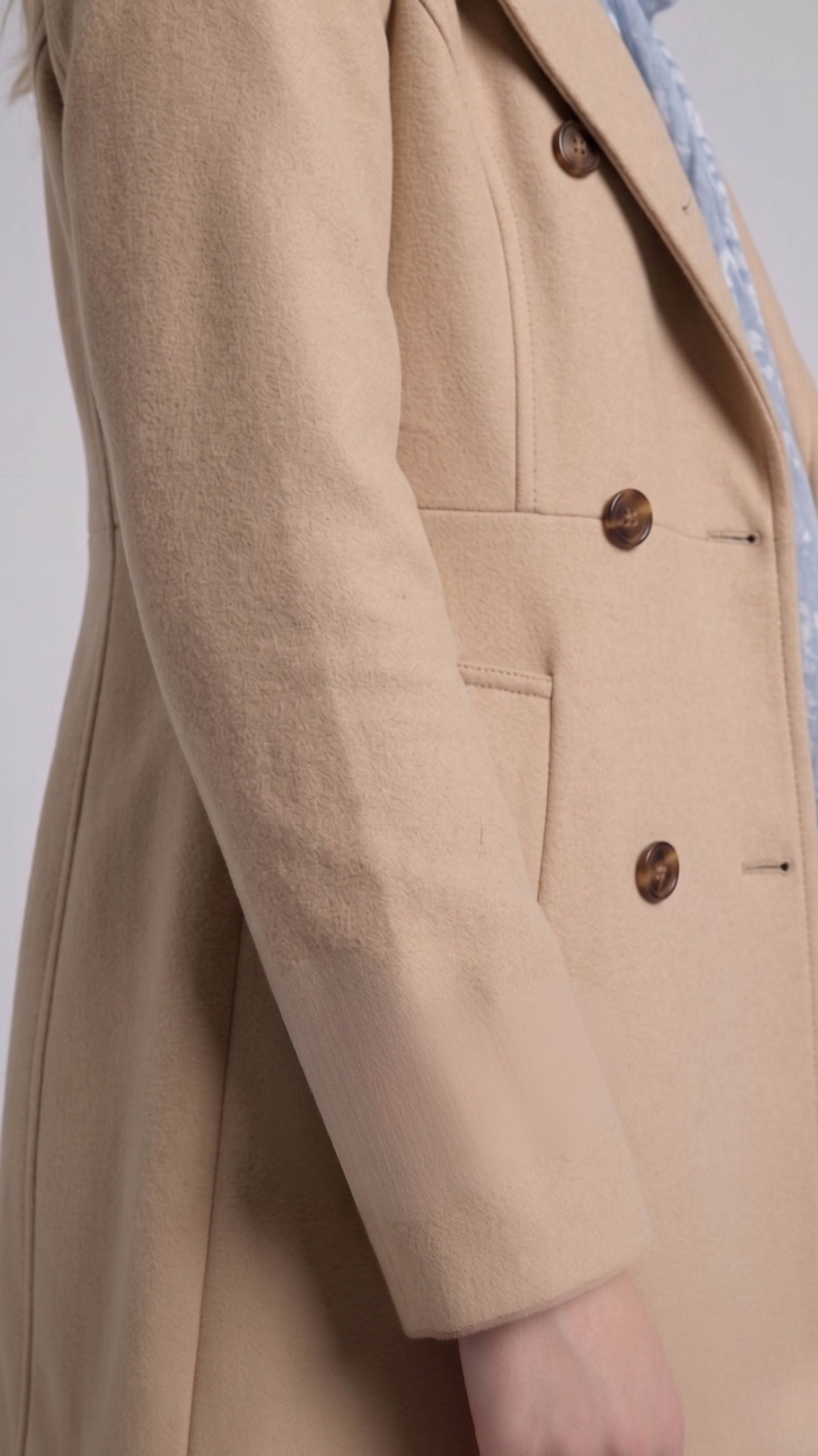 Close-up shot highlighting the soft weave texture of the beige cotton fabric and high-quality contrast button detailing.