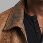 Close-up shot of the rugged texture and authentic fading on a light brown distressed leather coat.