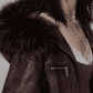 Detailed view of the relaxed oversized sleeve cuffs and lower hemline on a dark red leather coat highlighted with soft black fur lining.