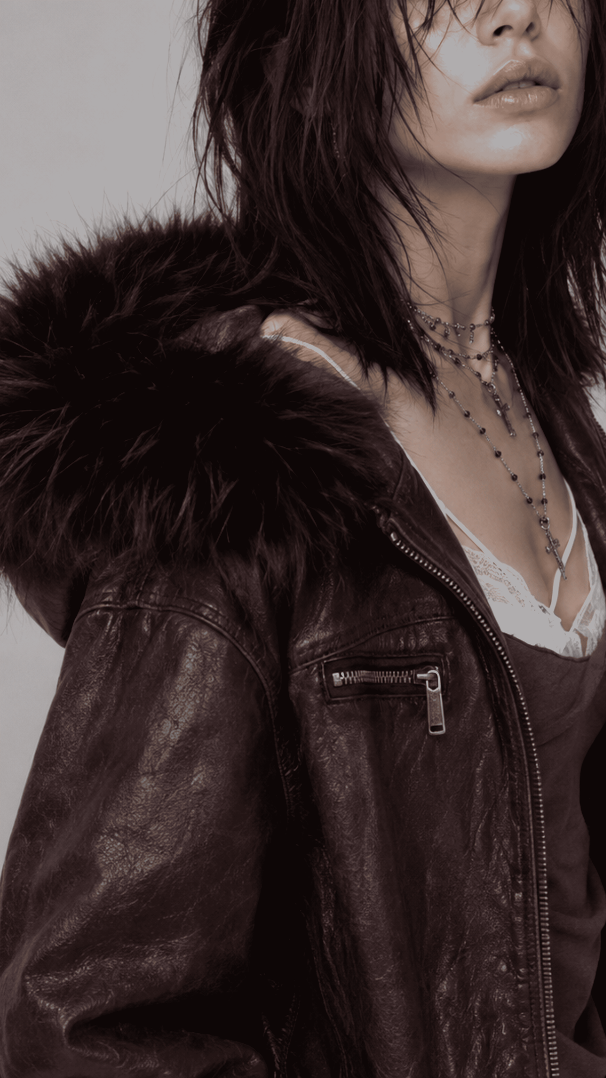 Detailed view of the relaxed oversized sleeve cuffs and lower hemline on a dark red leather coat highlighted with soft black fur lining.