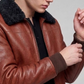 Macro detail close-up showing the rich grain of the cognac tan leather contrasting against the dense plush black shearling lapel texture.