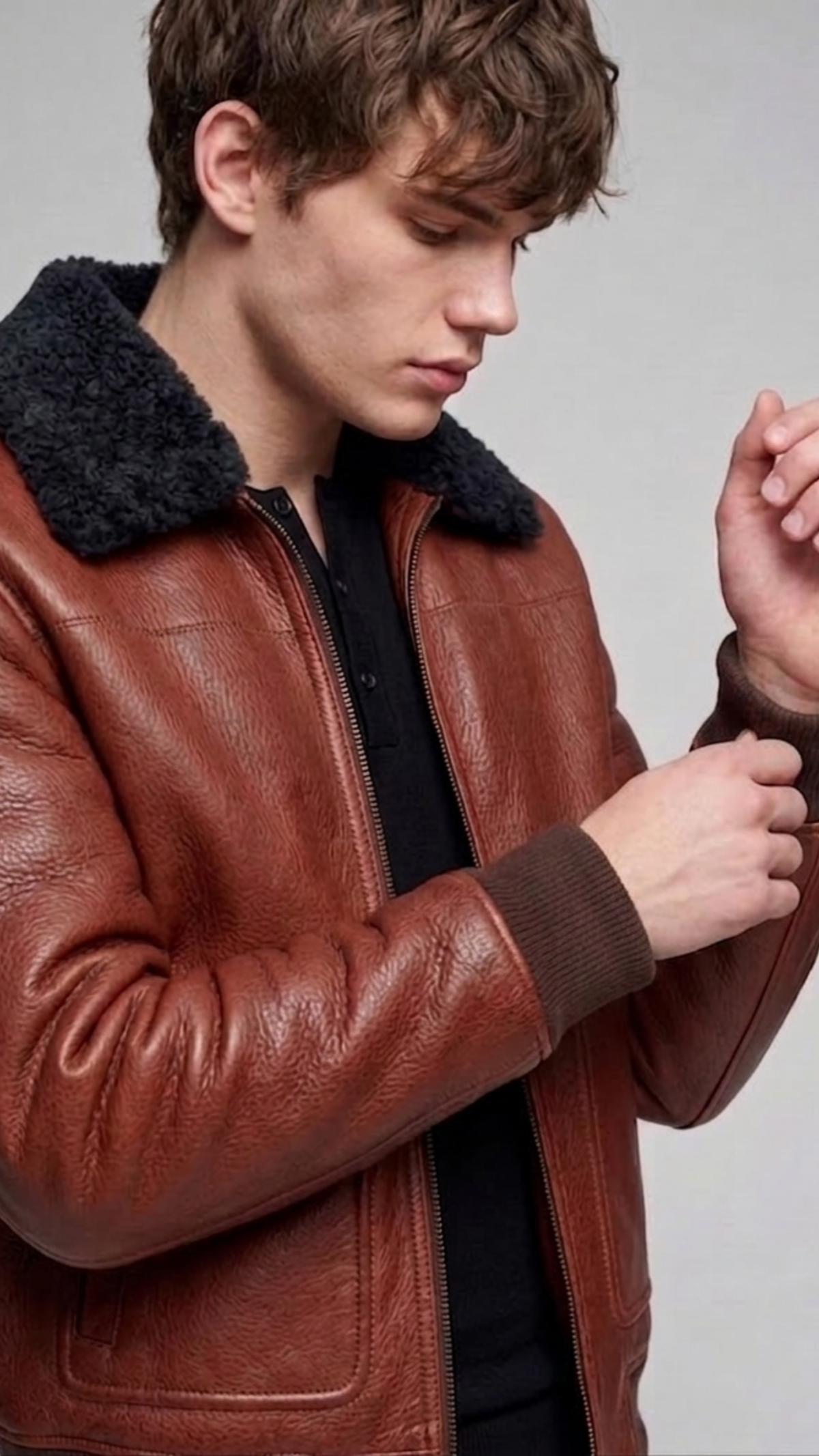 Macro detail close-up showing the rich grain of the cognac tan leather contrasting against the dense plush black shearling lapel texture.