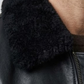 Close-up micro detail focusing on the soft, dense texture of the black shearling collar contrasted against the smooth premium leather.