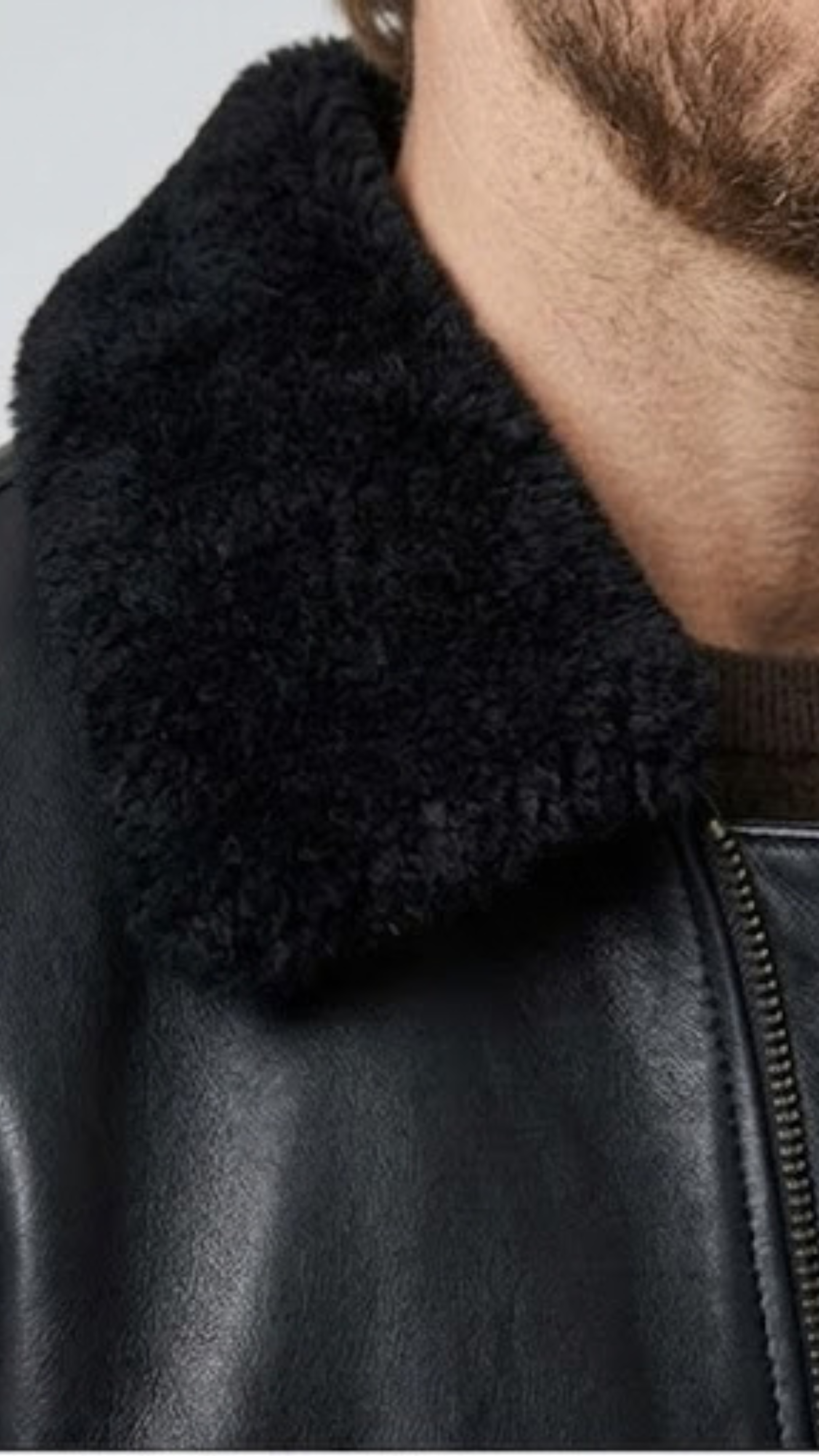 Close-up micro detail focusing on the soft, dense texture of the black shearling collar contrasted against the smooth premium leather.