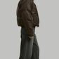 a modern chocolate brown streetwear puffer jacket styled with minimalist winter apparel.