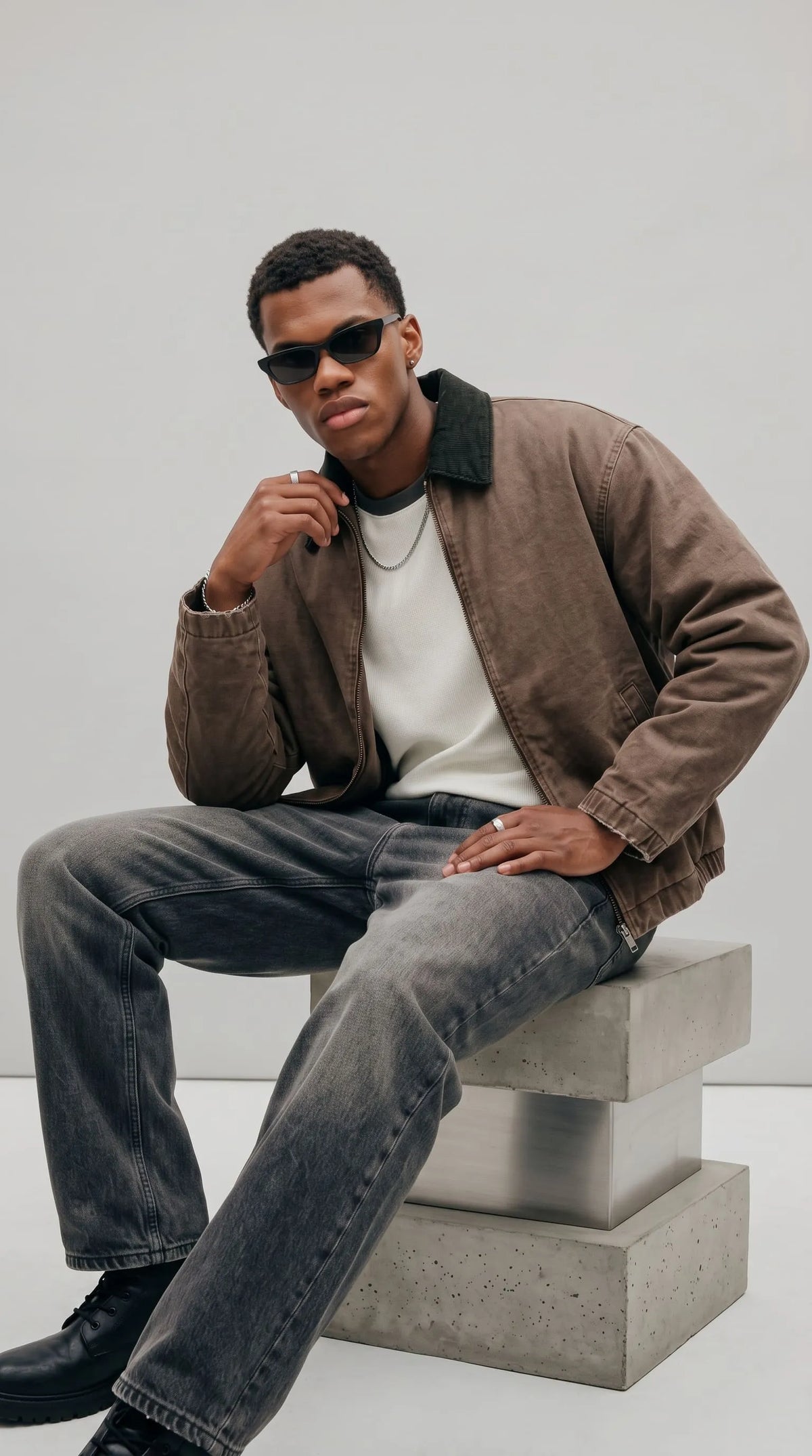 JACKERO brown cotton canvas jacket styled with charcoal washed denim and a minimal white T-shirt, showcasing a relaxed waist-length silhouette and dark textured collar for effortless contemporary streetwear.