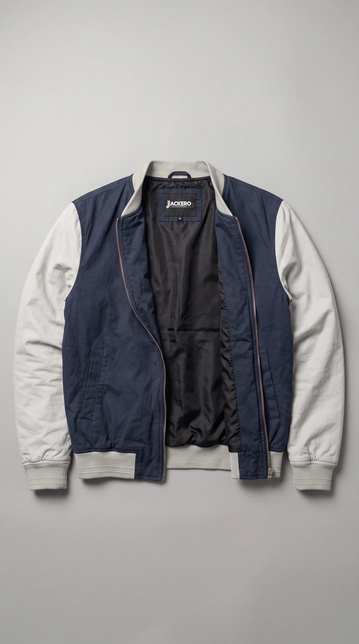 JACKERO dark navy-blue and grey cotton bomber jacket displayed open to reveal its smooth dark inner lining and signature neck label, with light-grey sleeves, ribbed collar and waistband, two side welt pockets and a full-length metal zipper.