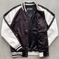 Jackero black and white tricolor varsity jacket beautifully showcased against a clean, minimalist studio backdrop.