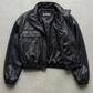 Jackero contemporary black leather cropped jacket beautifully presented against a clean, minimalist studio backdrop.