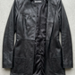 Jackero contemporary long-line black leather trench coat beautifully presented against a clean, professional studio backdrop.