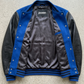 Jackero blue suede and black leather varsity jacket beautifully presented against a clean, minimalist studio backdrop.