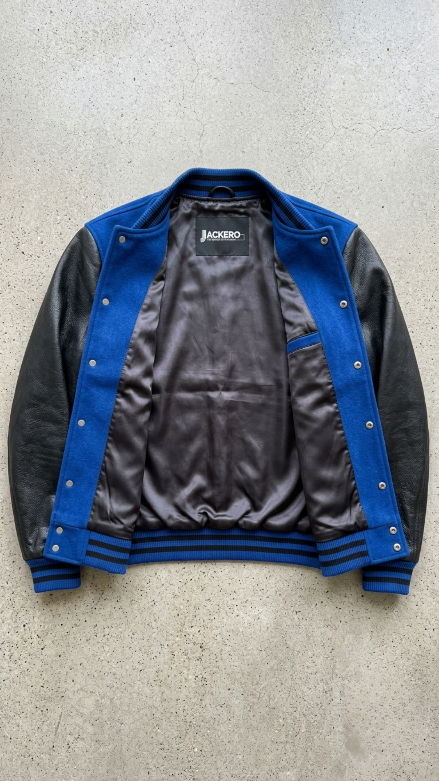 Jackero blue suede and black leather varsity jacket beautifully presented against a clean, minimalist studio backdrop.
