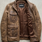 Jackero brown distressed leather field jacket with multi-pocket design beautifully presented against a clean, minimalist studio backdrop.