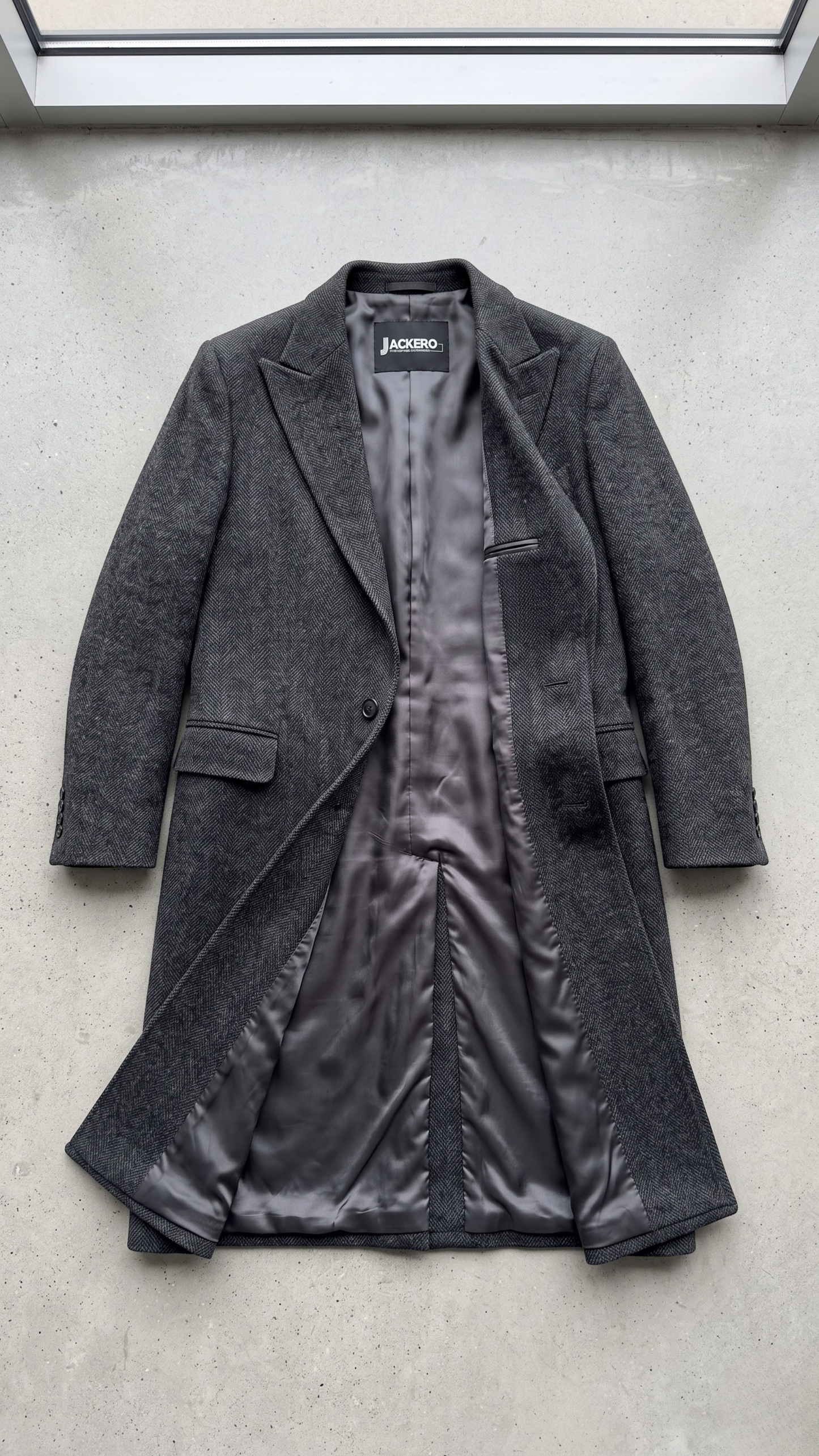 Jackero dark grey wool overcoat beautifully presented against a clean, minimalist studio backdrop.