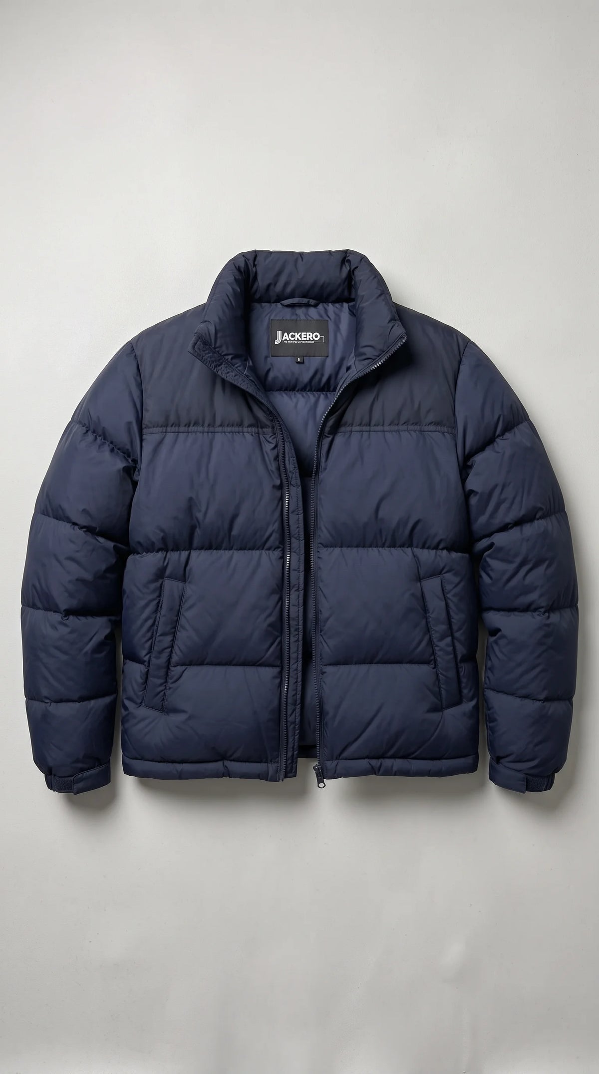 A navy blue puffer jacket with horizontal quilting, a high collar, and a front zipper, shown flat against a light gray background. The JACKERO brand name is visible on the inner neck label.