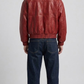 Model wearing a stylish red leather bomber jacket paired with men's vintage blue denim boot-cut jeans.