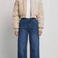 Front full view of premium light beige silk cotton cropped jacket highlighting the clean short waist-length cut and minimalist center zip closure.